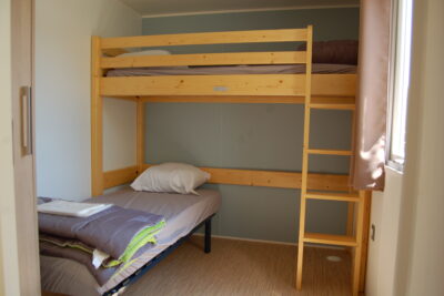 Chambre 2 personnes du mobil-home Optiméo. Deux lits simples : un en hauteur, l'autre en bas. - Agrandir l'image 6 sur 8, fenêtre modale