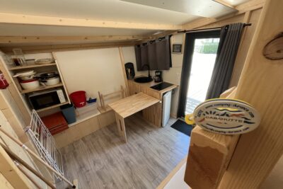 Intérieur de Caba'hutte avec évier et plaque induction, table et bancs - Agrandir l'image 1 sur 3, fenêtre modale