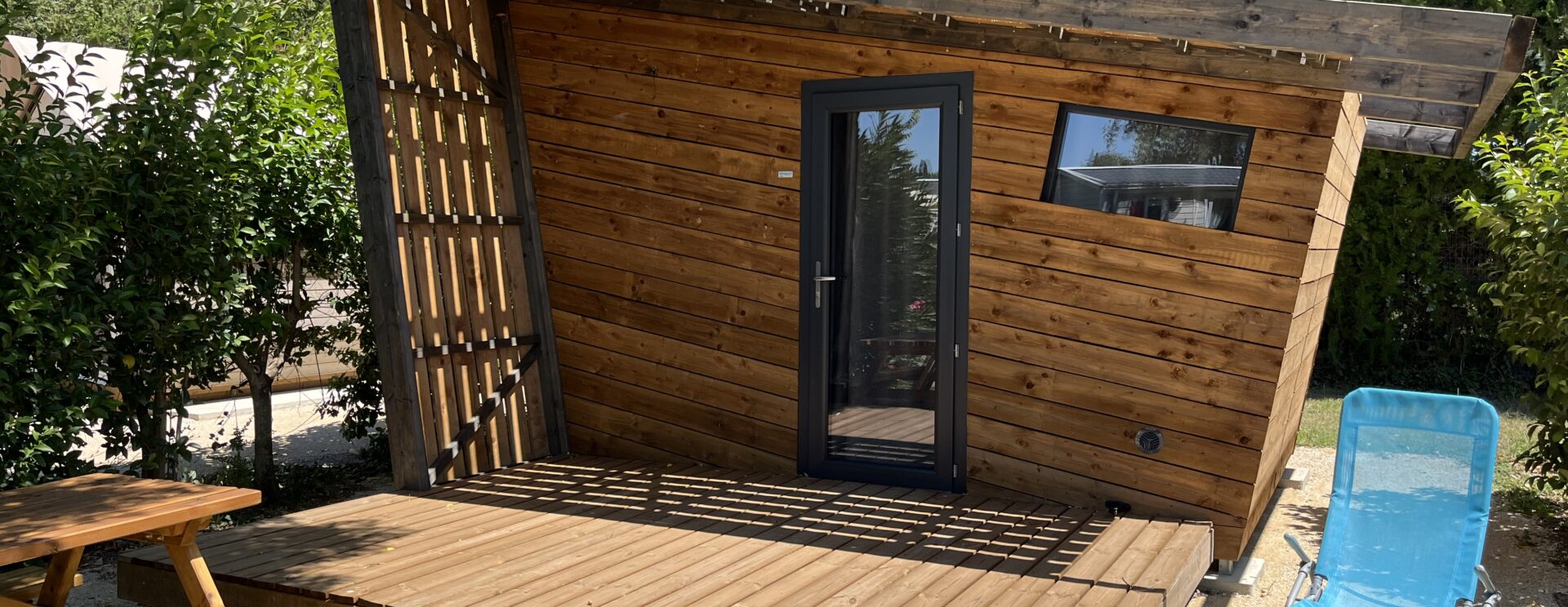 Cabane en bois avec terrasse, table picknick et chaise longue bleu